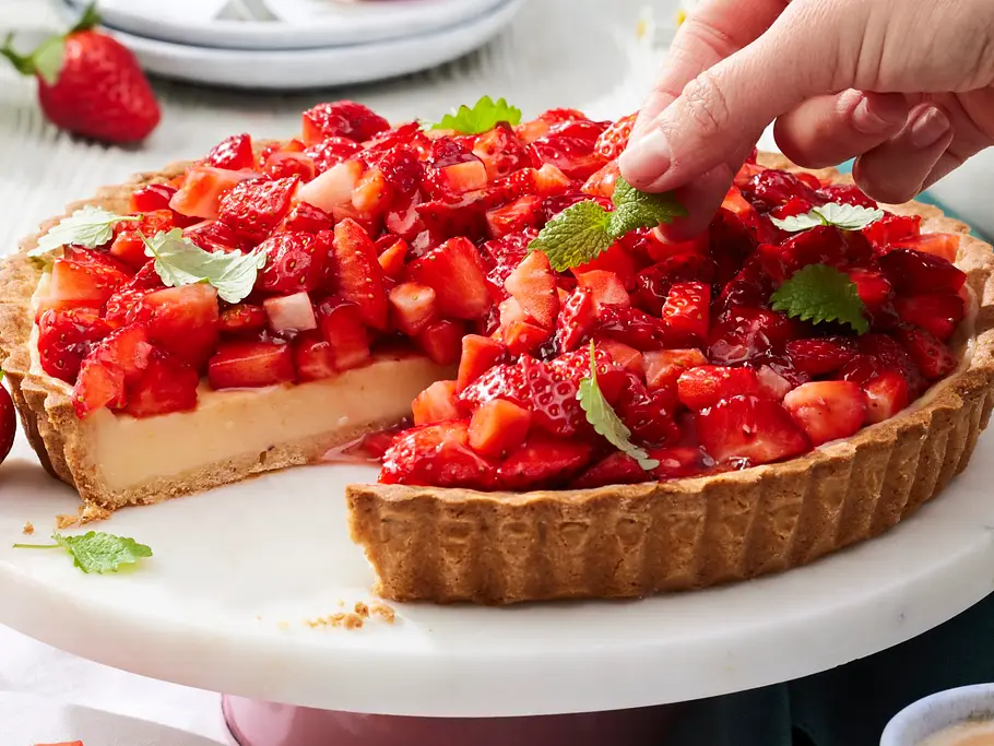Erdbeer-Zitronen-Tarte mit knusprigem Mürbeteigboden, cremiger Zitronenfüllung und frischen, gewürfelten Erdbeeren, serviert auf einer weißen Tortenplatte.