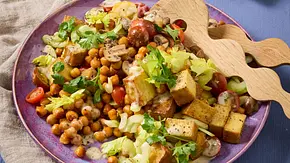 Lauwarmer Salat aus gebratenem Tofu, gerösteten Kichererbsen, Sellerie, Champignons und Kirschtomaten auf einem lila Teller, garniert mit frischen Kräutern. Daneben Holzsalatbesteck auf einer Leinenserviette. - Foto: LECKER @ Bauer Media Group Lauwarmer Salat aus gebratenem Tofu, gerösteten Kichererbsen, Sellerie, Champignons und Kirschtomaten auf einem lila Teller, garniert mit frischen Kräutern. Daneben Holzsalatbesteck auf einer Leinenserviette. - Foto: LECKER @ Bauer Media Group