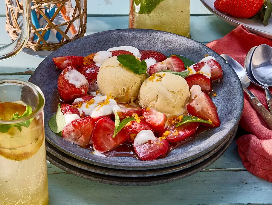Marshmallow-Erdbeeren vom Grill mit Vanilleeis Auf einem kleinen Teller liegen gegrillte Erdbeeren mit geschmolzenen Marshmallow, garniert mit 2 Kugeln Vanilleeis