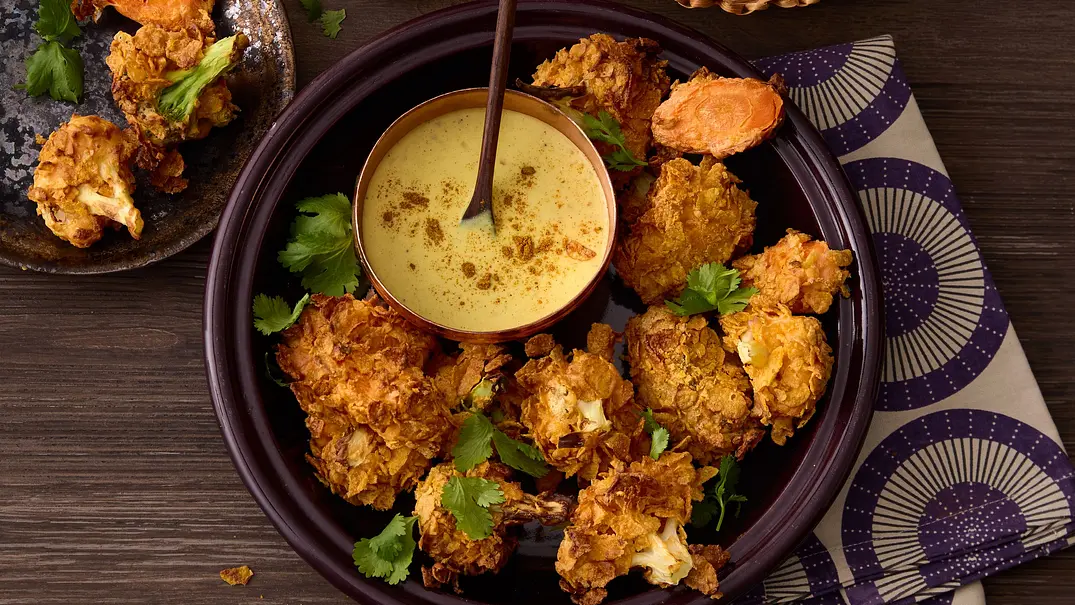 Knusprig frittiertes Gemüse im goldenen Cornflakes-Mantel auf einem dunklen Teller, serviert mit cremigem Dip in einer Schale und frischem Fladenbrot im Korb. - Foto: House of Food / StockFood Studios / Julia Hoersch, Knusprig frittiertes Gemüse im goldenen Cornflakes-Mantel auf einem dunklen Teller, serviert mit cremigem Dip in einer Schale und frischem Fladenbrot im Korb. - Foto: House of Food / StockFood Studios / Julia Hoersch,
