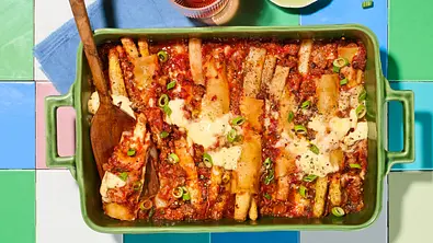 In einer Auflaufform werden Cannelloni mit Spargel in Tomatensoße überbacken und mit Frühlingszwiebeln bestreut. - Foto: House of Food / StockFood Studios / Meike Bergmann
