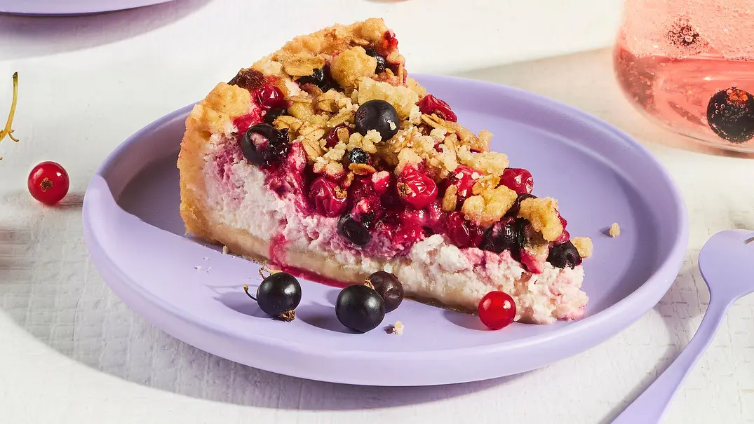 Drei Stücke Johannisbeerkuchen mit Schmandcreme und goldenen Streuseln auf fliederfarbenen Tellern, dekoriert mit frischen roten und schwarzen Johannisbeeren, daneben ein Glas Lillet-Drink. - Foto: StockFood Studios / Meike Bergmann