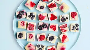 Verschiedene gefrorene Frozen-Yogurt-Würfel mit bunten Beeren auf einem runden, hellblauen Teller. - Foto: House of Food / StockFood Studios / Meike Bergmann Verschiedene gefrorene Frozen-Yogurt-Würfel mit bunten Beeren auf einem runden, hellblauen Teller. - Foto: House of Food / StockFood Studios / Meike Bergmann