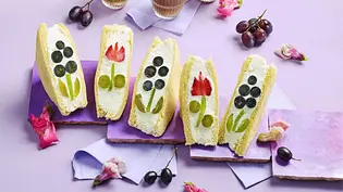 Brioche-Sandwiches, gefüllt mit Creme und frischem Obst wie Trauben und Erdbeeren, kunstvoll zu Blumenmotiven arrangiert, auf pastellfarbenen Unterlagen serviert. - Foto: LECKER @ Bauer Media Group