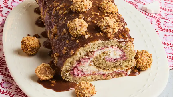 Glühwein-Haselnuss-Rolle mit Haselnuss-Pralinen verziert. - Foto: StockFood Studios / Meike Bergmann
