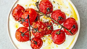 Cremig aufgeschlagener Feta serviert in einer flachen, hellen Schale, getoppt mit gerösteten Kirschtomaten am Zweig, verfeinert mit Olivenöl und Zitronenzesten. - Foto: Simone Neufing/MOE‘S QUICK & EASY FOOD Cremig aufgeschlagener Feta serviert in einer flachen, hellen Schale, getoppt mit gerösteten Kirschtomaten am Zweig, verfeinert mit Olivenöl und Zitronenzesten. - Foto: Simone Neufing/MOE‘S QUICK & EASY FOOD