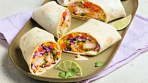 Vier Stücke Fischstäbchen-Wraps, gefüllt mit knusprigen Fischstäbchen, buntem Gemüse und Soße, angerichtet auf einem ovalen, grünen Teller mit etwas Limette und frischer Petersilie als Dekoration. - Foto: LECKER @ Bauer Media Group