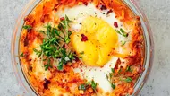 Gebackenes Ei auf einer cremigen Mischung aus geriebener Süßkartoffel und Käse, garniert mit frischem Thymian, serviert in einer runden Glasform auf heller Steinplatte. - Foto: Simone Neufing/MOE‘S QUICK & EASY FOOD Gebackenes Ei auf einer cremigen Mischung aus geriebener Süßkartoffel und Käse, garniert mit frischem Thymian, serviert in einer runden Glasform auf heller Steinplatte. - Foto: Simone Neufing/MOE‘S QUICK & EASY FOOD
