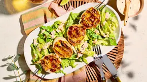 Knusprige Burrito-Taler auf einem Bett aus grünem Salat, angerichtet auf einem ovalen, weißen Teller mit Dressing und Limettenstücken, dazu Holzbesteck. - Foto: House of Food / StockFood Studios / Meike Bergmann