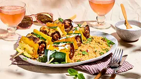 Bunte Ratatouille-Gemüsespieße mit Zucchini und Paprika, serviert auf lockerem Couscous auf einem weißen Teller mit Holzbesteck und gestreifter Serviette. - Foto: House of Food / StockFood Studios / Meike Bergmann Bunte Ratatouille-Gemüsespieße mit Zucchini und Paprika, serviert auf lockerem Couscous auf einem weißen Teller mit Holzbesteck und gestreifter Serviette. - Foto: House of Food / StockFood Studios / Meike Bergmann