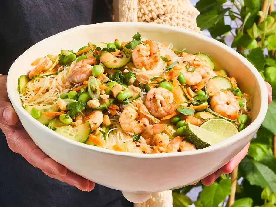 Glasnudelsalat mit Garnelen und Saté-Sauce Große Schüssel mit Glasnudelsalat, belegt mit Garnelen, frischem Gemüse, Kräutern, Limetten und Erdnüssen, alles vermischt mit Saté-Sauce.