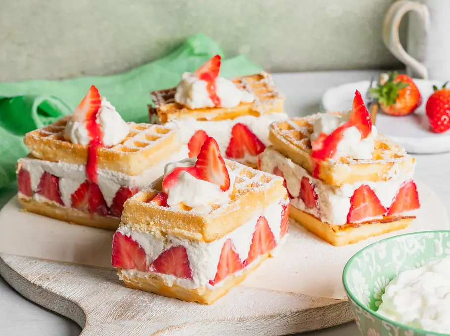 4 Stücke vom Erdbeer-Waffelkuchen auf einem Holzbretttchen