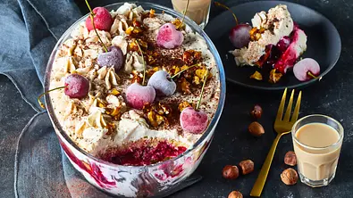 Ein Schichtdessert mit Kirschen und Nüssen steht in einer Glasschale neben einer Portion auf einem Teller und zwei Gläsern. - Foto: StockFood Studios / Meike Bergmann Ein Schichtdessert mit Kirschen und Nüssen steht in einer Glasschale neben einer Portion auf einem Teller und zwei Gläsern. - Foto: StockFood Studios / Meike Bergmann