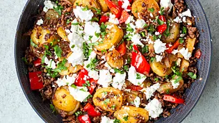 Bratkartoffel-Pfanne mit goldbraunen Kartoffelscheiben, gebratenem Hackfleisch, roten Paprikastücken und zerbröseltem Feta, in einer dunklen Pfanne angerichtet. - Foto: Simone Neufing/MOE‘S QUICK & EASY FOOD Bratkartoffel-Pfanne mit goldbraunen Kartoffelscheiben, gebratenem Hackfleisch, roten Paprikastücken und zerbröseltem Feta, in einer dunklen Pfanne angerichtet. - Foto: Simone Neufing/MOE‘S QUICK & EASY FOOD