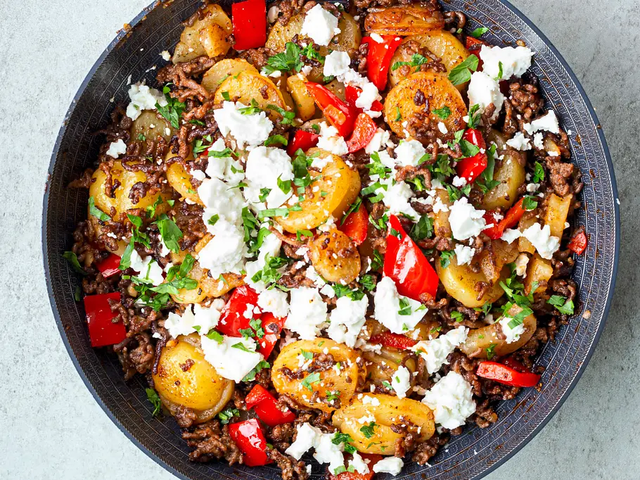 Bratkartoffel-Pfanne mit Hackfleisch und Feta Bratkartoffel-Pfanne mit goldbraunen Kartoffelscheiben, gebratenem Hackfleisch, roten Paprikastücken und zerbröseltem Feta, in einer dunklen Pfanne angerichtet.
