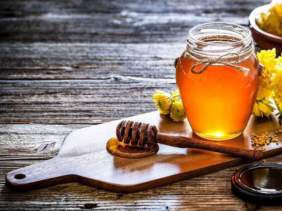 Honiglöffel und Honig im Glas auf einem Holzbrett