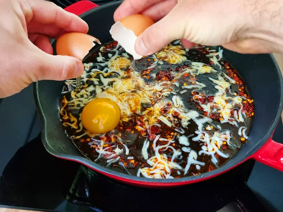 Hot Honey Eggs - Eier aufschlagen Ein Ei wird in der Pfanne aufgeschlagen