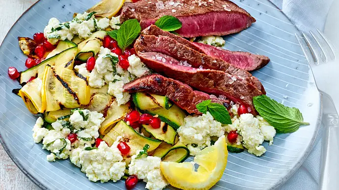 Ein blauer Teller mit gebratenen Zucchini-Streifen, Feta, Granatapfel und Hüftsteak-Streifen. - Foto: LECKER @ Bauer Media Group Ein blauer Teller mit gebratenen Zucchini-Streifen, Feta, Granatapfel und Hüftsteak-Streifen. - Foto: LECKER @ Bauer Media Group