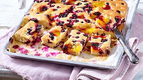 Rührkuchen vom Blech mit schwarzen Johannisbeeren, ein Teil davon in Stücke geschnitten - Foto: House of Food / Bauer Food Experts KG