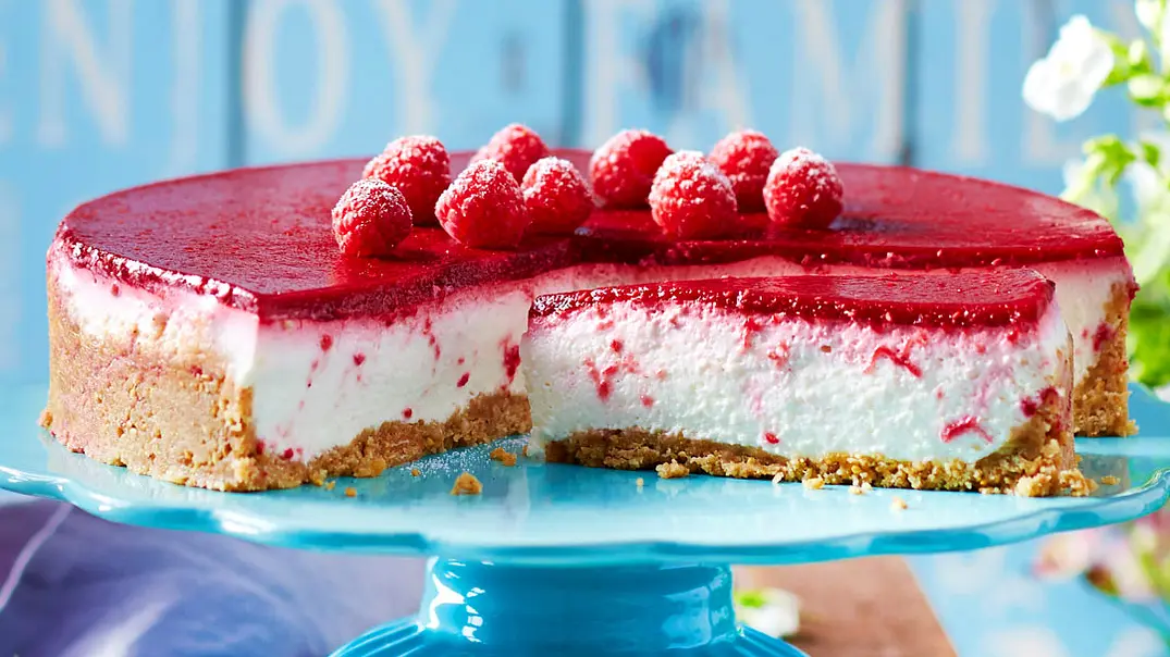 Angeschnittene Joghurt-Himbeertorte ist auf einer blauen Etagere serviert. - Foto: LECKER @ Bauer Media Group Angeschnittene Joghurt-Himbeertorte ist auf einer blauen Etagere serviert. - Foto: LECKER @ Bauer Media Group