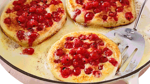3 mit roten Johannisbeeren belegte Pancakes in einer weißen Emaillepfanne mit schwarzem Rand - Foto: House of Food / Bauer Food Experts KG