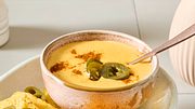 Ein Platte mit Nachos und einem Schälchen Käse-Dip für Nachos, garniert mit Jalapeno-Scheiben - Foto: House of Food / Bauer Food Experts KG