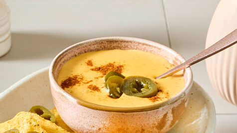 Ein Platte mit Nachos und einem Schälchen Käse-Dip für Nachos, garniert mit Jalapeno-Scheiben - Foto: House of Food / Bauer Food Experts KG