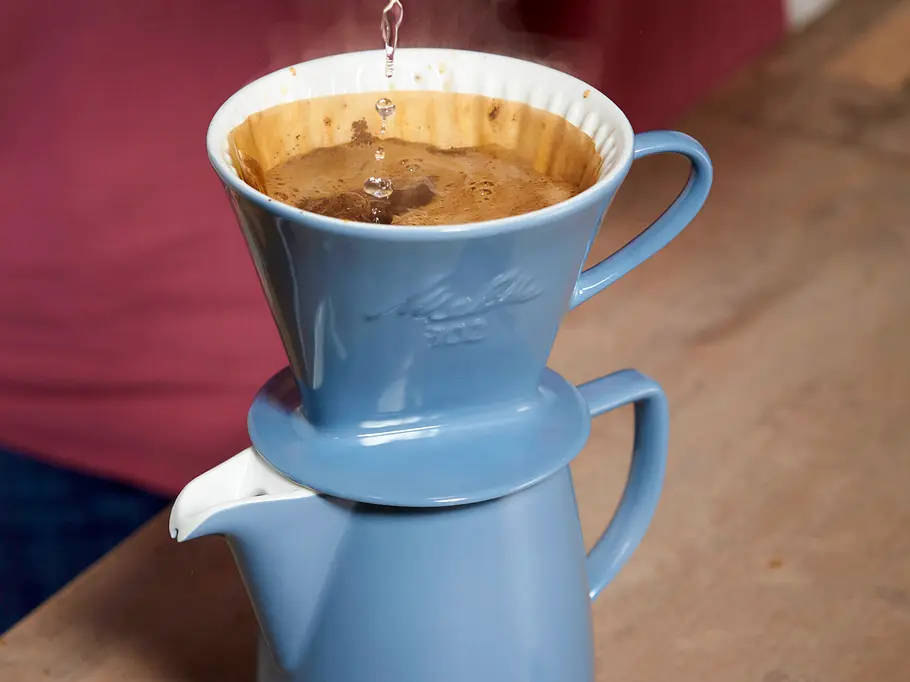 Steigende Kaffeepreise: 9 günstigere Alternativen mit und ohne Koffein Kaffeetasse mit Handfilter, Kaffee wird mit heißem Wasser frisch aufgebrüht.