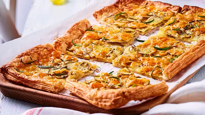 Eine goldbraun gebackene Kartoffel-Tarte auf weißem Backpapier. In sechs gleichgroße Stücke geschnitten. - Foto: LECKER @ Bauer Media Group Eine goldbraun gebackene Kartoffel-Tarte auf weißem Backpapier. In sechs gleichgroße Stücke geschnitten. - Foto: LECKER @ Bauer Media Group