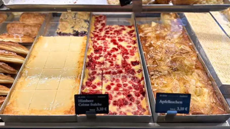 Kuchenauslage beim Bäcker: Schmandkuchen, Himbeerkuchen und Apfelkuchen