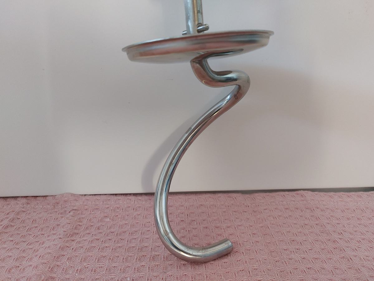 Der Knethaken der Kenwood Titanium Chef Baker Küchenmaschine liegt auf einem rosa Handtuch vor weißem Hintergrund.
