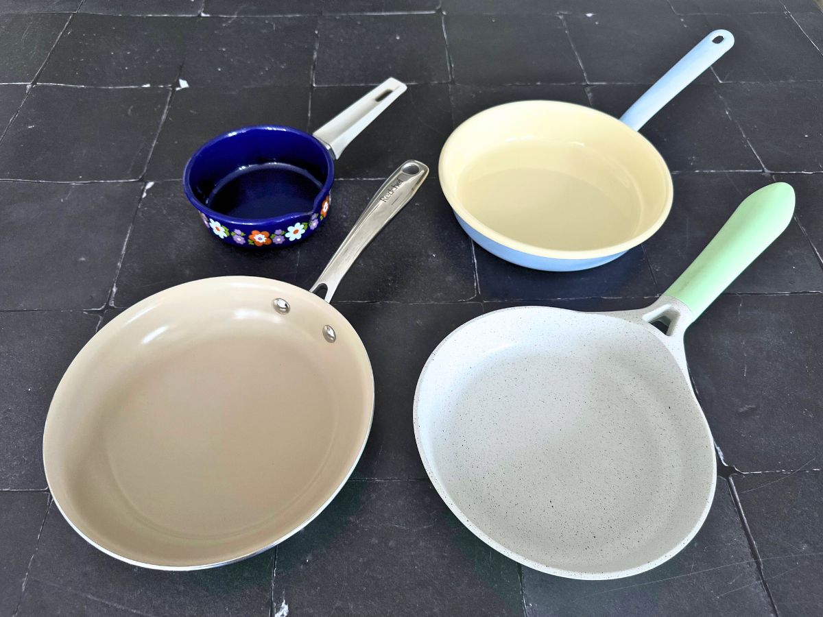 Topshot auf vier Aluminiumpfannen mit Keramik- oder Emaillebeschichtung in verschiedenen Größen und Farben