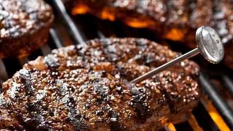 Jemand misst die Kerntemperatur des Steaks auf dem Grill - Foto: iStock/mphillips007