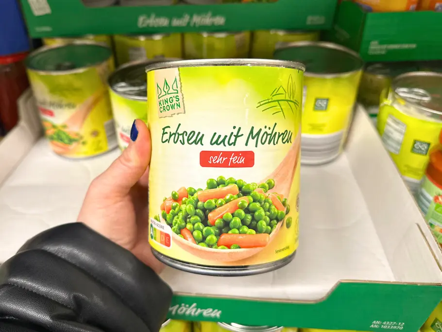 Eine Hand hält eine Dose King‘s Crown Erbsen mit Möhren von Aldi