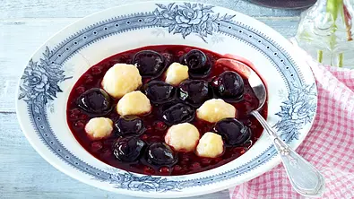 Kirsch-Johannisbeer-Kaltschale mit Mehlklößen in einem Suppenteller mit Suppenlöffel darin - Foto: LECKER @ Bauer Media Group