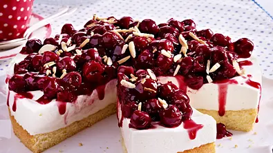 Runder Kirsch-Quark-Kuchen mit Mandelstiften bestreut und auf einem gewelltem weißem Teller serviert. - Foto: LECKER @ Bauer Media Group Runder Kirsch-Quark-Kuchen mit Mandelstiften bestreut und auf einem gewelltem weißem Teller serviert. - Foto: LECKER @ Bauer Media Group