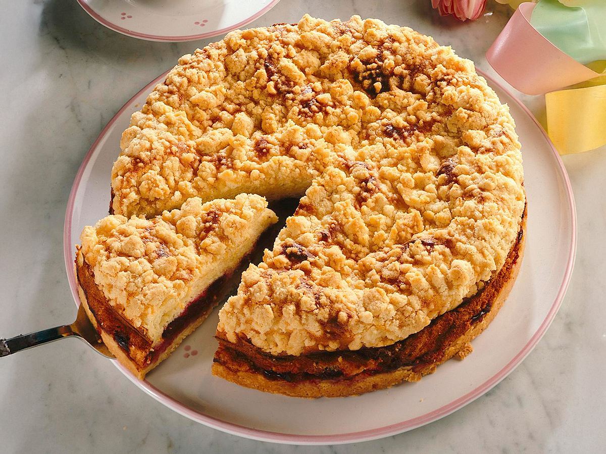 Kirsch-Streuselkuchen aus der Springform auf einem weißen Teller mit rosa Rand