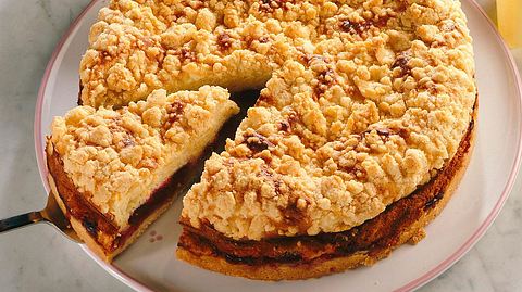 Kirsch-Streuselkuchen aus der Springform auf einem weißen Teller mit rosa Rand - Foto: Klemme