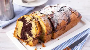 Klassischer Marmorkuchen mit Puderzucker bestäubt auf einer weißen Kuchenplatte. - Foto: ShowHeroes für LECKER @ Bauer Media Group Klassischer Marmorkuchen mit Puderzucker bestäubt auf einer weißen Kuchenplatte. - Foto: ShowHeroes für LECKER @ Bauer Media Group
