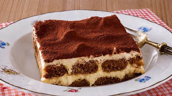 Ein tiefer Teller mit einem Stück Tiramisu steht auf einem Holztisch mit rot-weiß-kariertem Platz-Set - Foto: LECKER @ Bauer Media Group Ein tiefer Teller mit einem Stück Tiramisu steht auf einem Holztisch mit rot-weiß-kariertem Platz-Set - Foto: LECKER @ Bauer Media Group