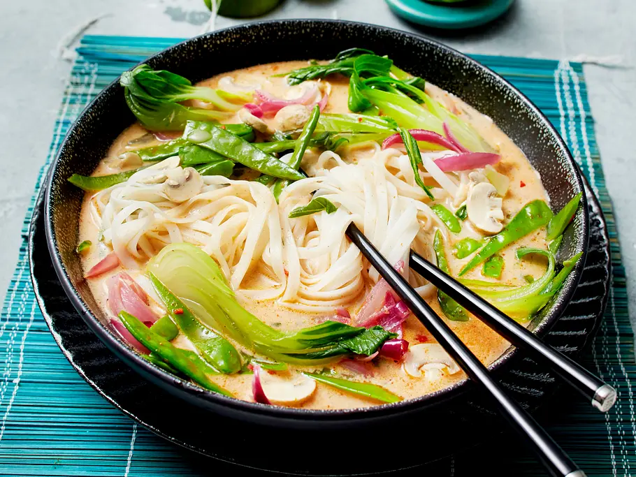 Kokossuppe mit Reisnudeln Rezept Kokossuppe mit Reisnudeln, Pak Choi und Zuckerschoten in einer großen Schüssel serviert.