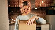 Junge Frau packt Paket in der Küche aus - Foto: LECKER.de/iStock (shurkin_son)