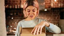 Junge Frau öffnet Karton in der Küche. - Foto: LECKER.de/iStock (shurkin_son)