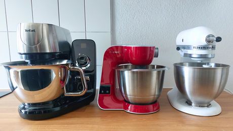 Drei Küchenmaschinen stehen nebeneinander: links eine schwarze von Tefal, in der Mitte eine rote von Bosch und rechts eine weiße von KitchenAid - Foto: LECKER @ Bauer Media Group / Nadja Demel