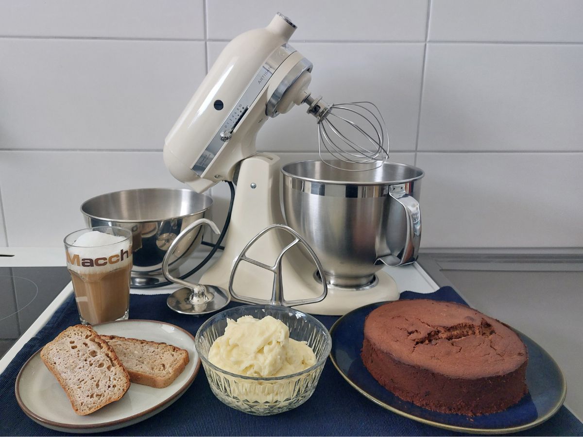 Küchenmaschine KitchenAid Artisan samt Rührwerkzeug und 3l-Schüssel mit Milchschaum, Brot, Kartoffelpüree und Kuchen.