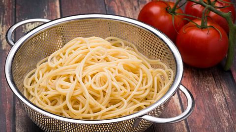 Spaghetti in einem Stahl-Küchensieb auf einer Holzoberfläche - Foto: iStock/huntconsulting