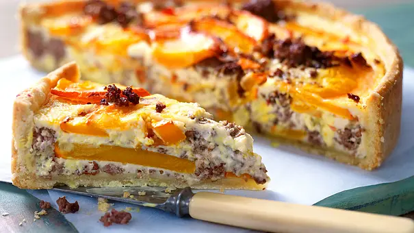 Angeschnittene Kürbis-Hack-Quiche auf einer weißen Servierplatte. Daneben ein Messer zum Anschneiden. - Foto: LECKER @ Bauer Media Group Angeschnittene Kürbis-Hack-Quiche auf einer weißen Servierplatte. Daneben ein Messer zum Anschneiden. - Foto: LECKER @ Bauer Media Group