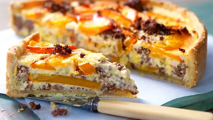 Angeschnittene Kürbis-Hack-Quiche auf einer weißen Servierplatte. Daneben ein Messer zum Anschneiden. - Foto: LECKER @ Bauer Media Group Angeschnittene Kürbis-Hack-Quiche auf einer weißen Servierplatte. Daneben ein Messer zum Anschneiden. - Foto: LECKER @ Bauer Media Group