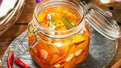 Kürbis-Pickles mit Knoblauch, Chili und Lorbeerblättern in einem Bügelglas serviert. und  - Foto: LECKER @ Bauer Media Group