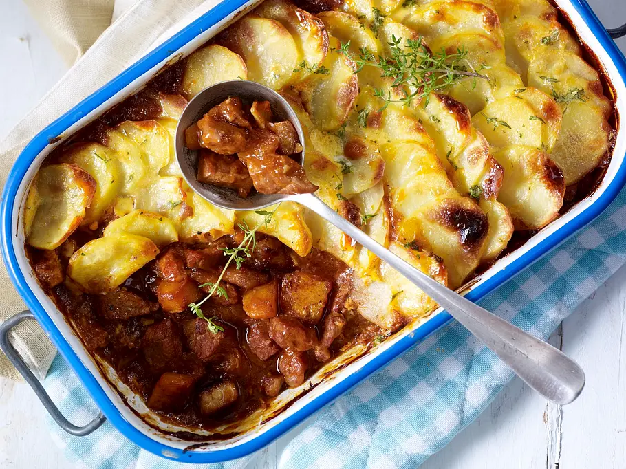 Kürbis-Schmorgulasch in einer großen Auflaufform mit Kartoffel-Käse-Kruste.
